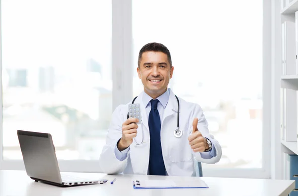 Médico sonriente con tabletas que muestran los pulgares hacia arriba — Foto de Stock