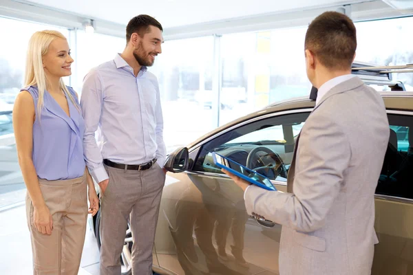 Gelukkige paar met autodealer in autoshow of salon — Stockfoto