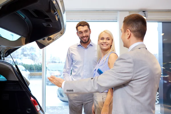 Glückliches Paar mit Autohändler in Auto-Show oder Salon — Stockfoto