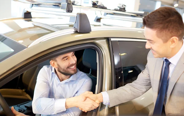 Gelukkig man met autodealer in autoshow of salon — Stockfoto