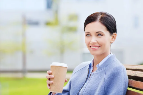 Lächelnde Frau, die draußen Kaffee trinkt — Stockfoto