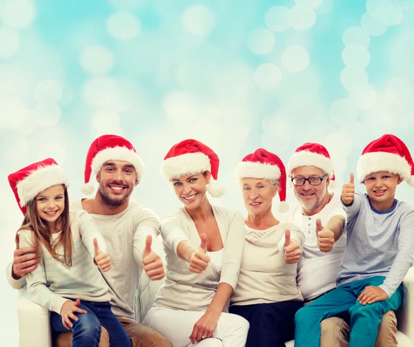Famiglia felice in cappelli di Babbo Natale mostrando pollici in su Foto Stock Royalty Free