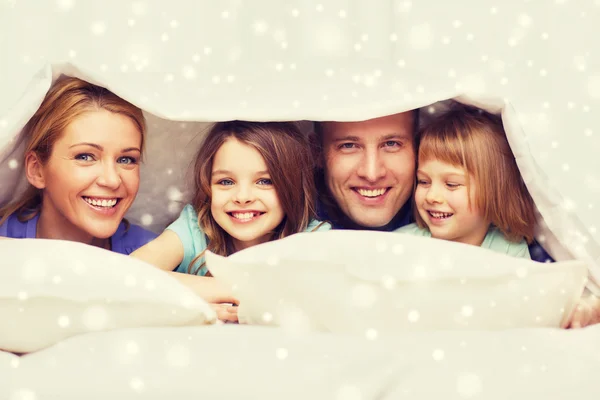 Happy family with two kids under blanket at home Stock Image
