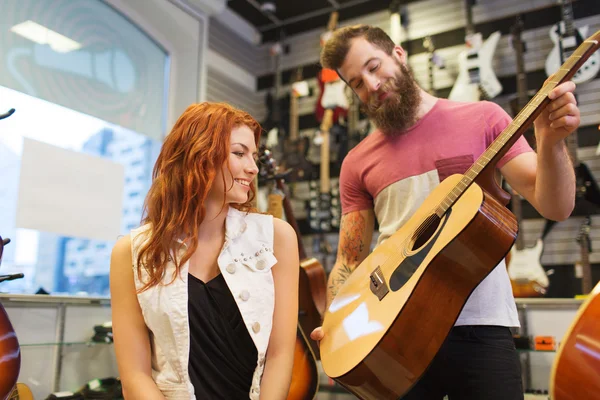 Musikerpaar mit Gitarre im Musikladen Stockbild