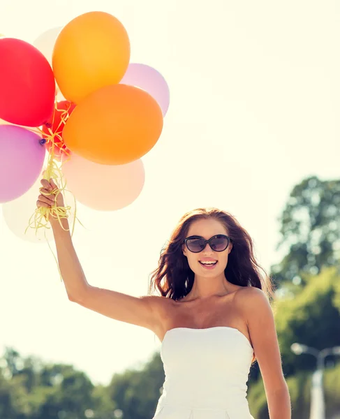 Leende ung kvinna i solglasögon med ballonger — Stockfoto