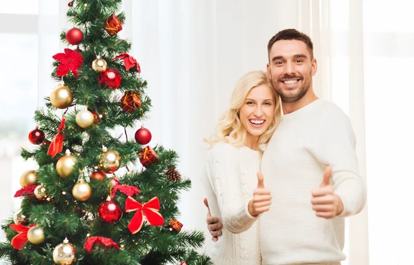 Ευτυχισμένο ζευγάρι που δείχνει τους αντίχειρες με Χριστουγεννιάτικο δέντρο — Φωτογραφία Αρχείου