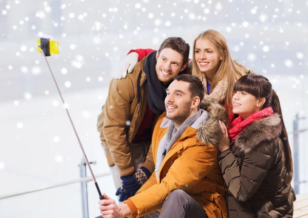 Gelukkige vrienden met smartphone op ijsbaan — Stockfoto