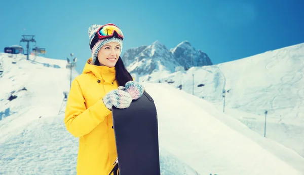 Happy young woman with snowboard over mountains — Stock Photo, Image