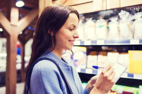 Mujer feliz con bloc de notas en el mercado — Foto de Stock