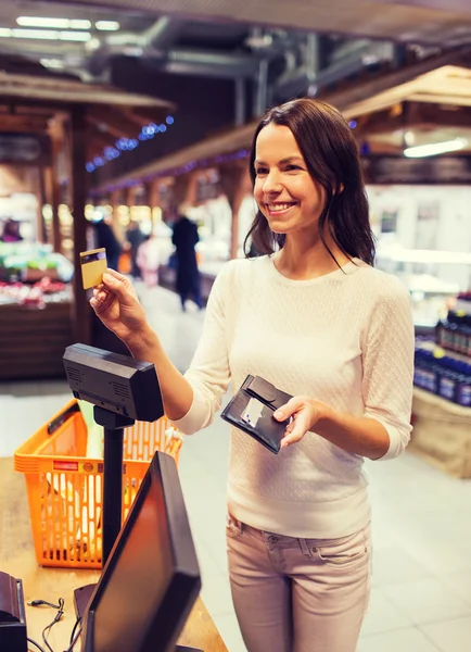 Glückliche Frau mit Kreditkarte kauft Lebensmittel auf dem Markt — Stockfoto