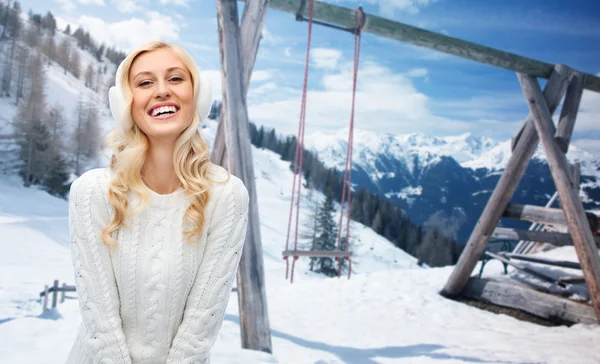 Lachende jonge vrouw in winter oorkappen en trui — Stockfoto