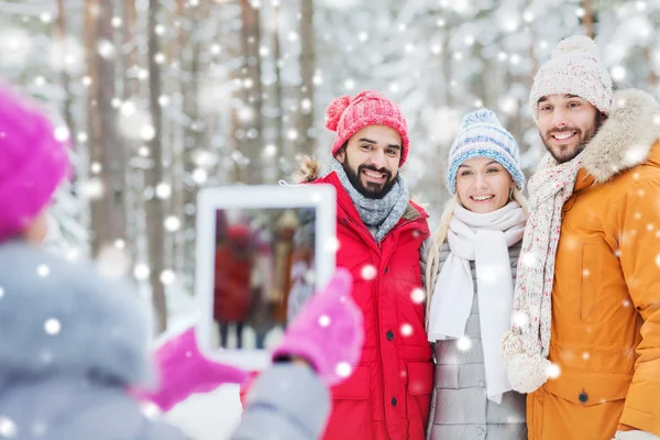 Усміхнені друзі з планшетним ПК в зимовому лісі — стокове фото