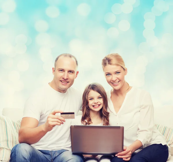 Família feliz com computador portátil e cartão de crédito — Fotografia de Stock