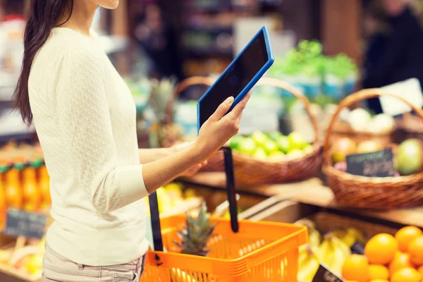 Mulher com cesta e tablet pc no mercado — Fotografia de Stock