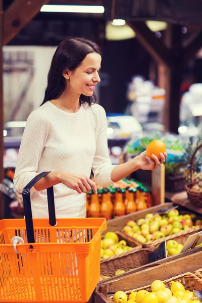 Happy young woman with food basket in market — Stock Photo, Image