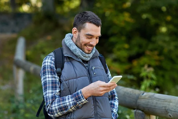 Glücklicher Mann mit Rucksack und Smartphone im Freien — Stockfoto
