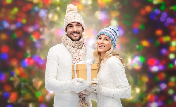 Smiling couple in winter clothes with gift box — Stock Photo, Image