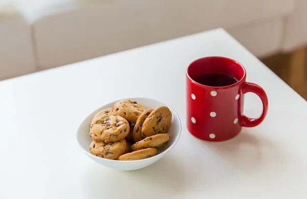 Close up of oat cookies and red tea cup on table — Stock Photo, Image