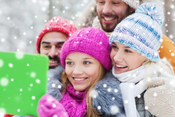 Усміхнені друзі з планшетним ПК в зимовому лісі — стокове фото