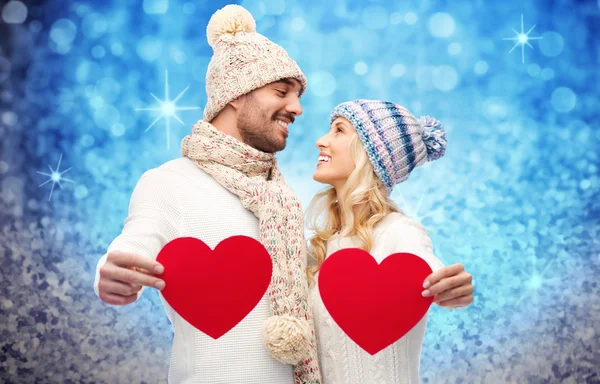 Χαμογελώντας ζευγάρι στο χειμωνιάτικα ρούχα με κόκκινες καρδιές — Φωτογραφία Αρχείου