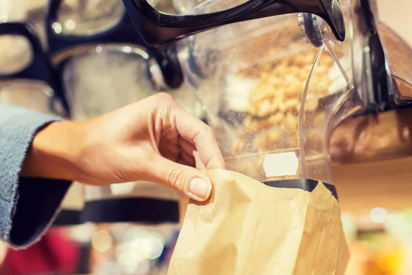 Primer plano de la mano verter las nueces a la bolsa de papel — Foto de Stock