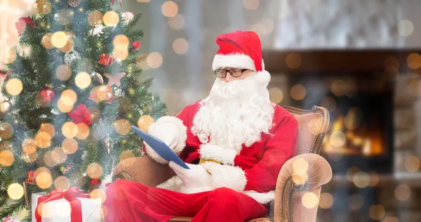 Санта-Клаус с планшетным ПК в кресле на дому — стоковое фото
