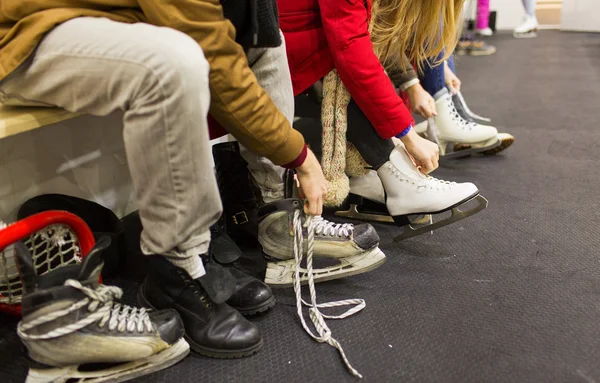 close up of friends wearing skates on skating rink