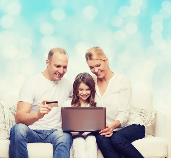 Familia feliz con ordenador portátil y tarjeta de crédito — Foto de Stock