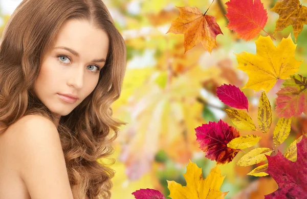 Красива молода жінка стикається з осіннім листям — стокове фото