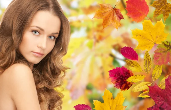 Belle jeune femme visage sur les feuilles d'automne — Photo