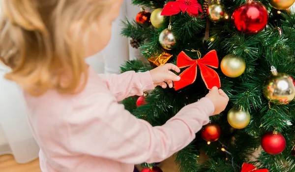 Nahaufnahme eines kleinen Mädchens, das den Weihnachtsbaum schmückt lizenzfreie Stockbilder