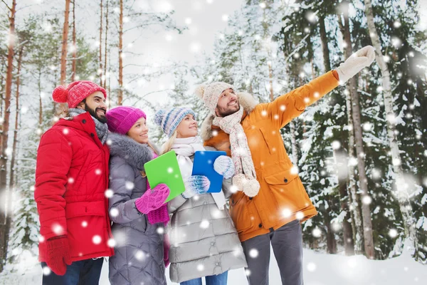 Amigos sorridentes com tablet pc na floresta de inverno — Fotografia de Stock