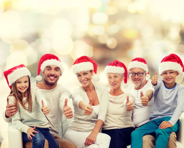 Happy family in santa hats showing thumbs up — Stock Photo, Image