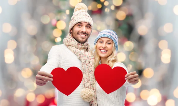 Coppia sorridente in abiti invernali con i cuori rossi — Foto Stock