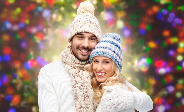 Happy couple in winter clothes hugging over lights — Stok fotoğraf