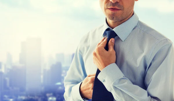 Close up de homem na camisa ajustando gravata no pescoço — Fotografia de Stock