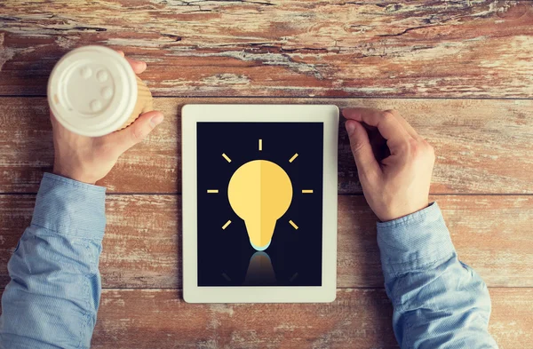 Close up of hands with ligting bulb on tablet pc — Stock Photo, Image