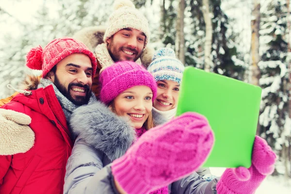 Amigos sorridentes com tablet pc na floresta de inverno — Fotografia de Stock