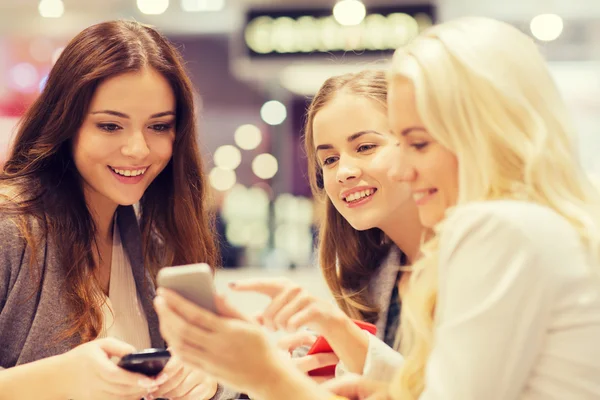 Mujeres felices con teléfonos inteligentes y tableta PC en el centro comercial —  Fotos de Stock