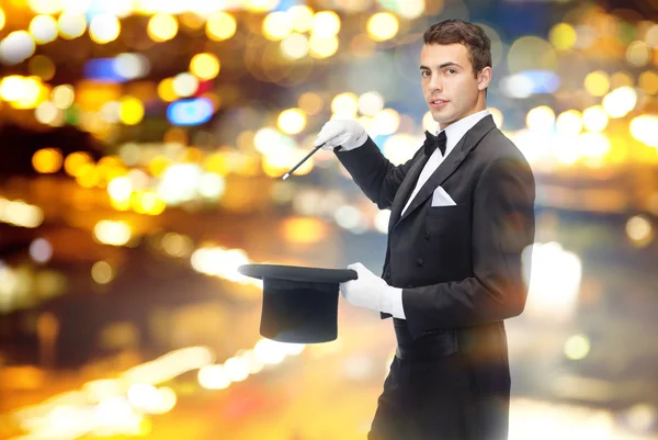 Magician in top hat with magic wand showing trick — Stock Photo, Image