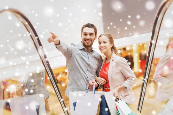 Casal com sacos de compras na escada rolante no shopping — Fotografia de Stock