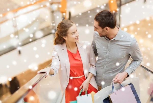 Casal com sacos de compras na escada rolante no shopping — Fotografia de Stock
