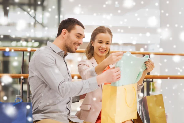 Feliz jovem casal com sacos de compras no shopping — Fotografia de Stock