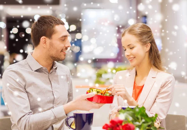 Gelukkige paar met heden en bloemen in winkelcentrum — Stockfoto