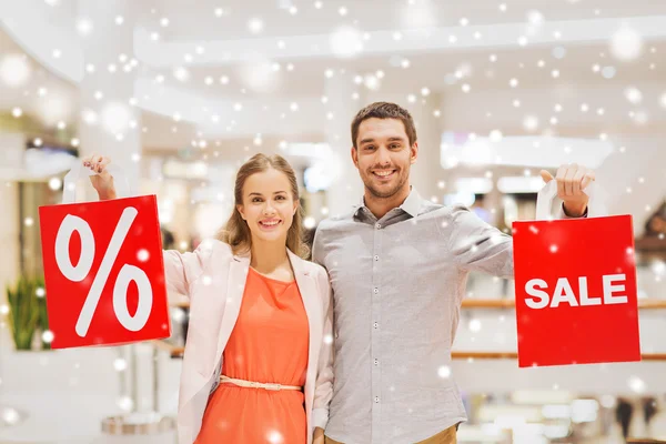 Glückliches junges Paar mit roten Einkaufstüten in Einkaufszentrum — Stockfoto