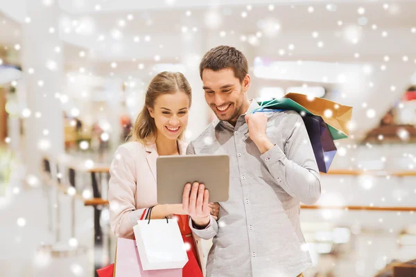 Pareja con tablet pc y bolsas de compras en el centro comercial —  Fotos de Stock