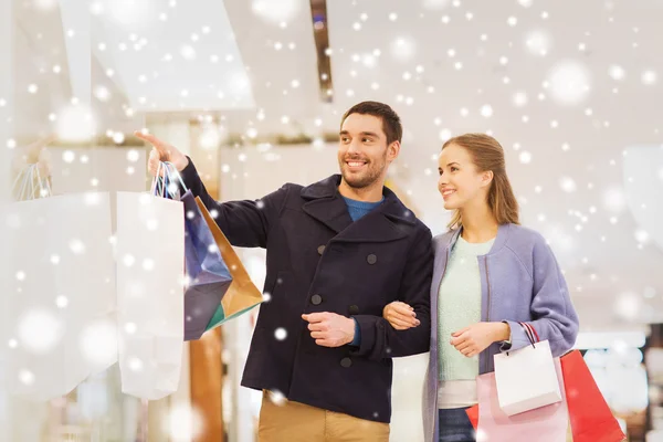 Feliz jovem casal com sacos de compras no shopping — Fotografia de Stock