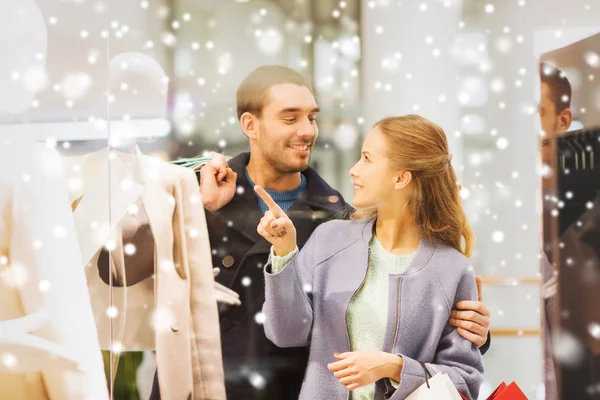 Feliz jovem casal com sacos de compras no shopping — Fotografia de Stock