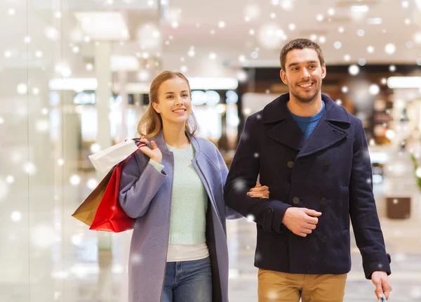 Feliz jovem casal com sacos de compras no shopping — Fotografia de Stock