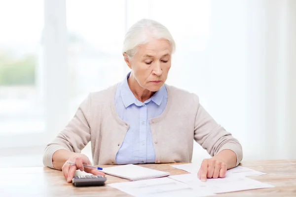 Mujer mayor con papeles y calculadora en casa —  Fotos de Stock